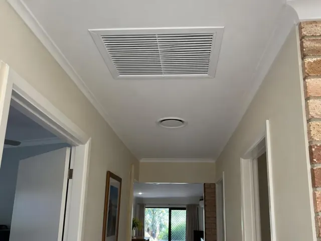 Ceiling return-air grille in a hallway with light walls and doorways in Burleigh Heads